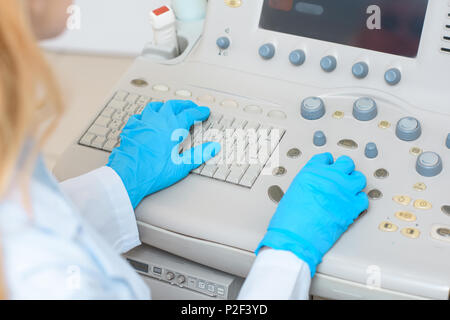 cropped shot of female obstetrician gynecologist in gloves working with ultrasonic scanner Stock Photo