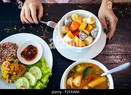 Thai traditional sour soup Tom Yam in vegetarian variation, curry rice and fruit salad in vegan restaurant in Bangkok Stock Photo