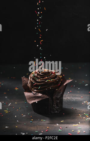 tasty chocolate cupcake with glaze and sugar spreading on table Stock Photo