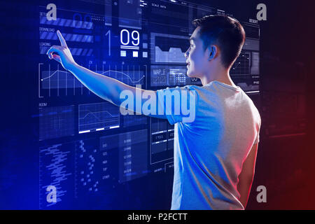 Emotional young man feeling impressed while touching the futuristic computer Stock Photo