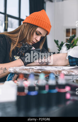 Woman creating tattoo on male arm Stock Photo