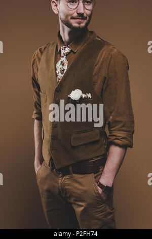 Young man in vintage styled clothes with boutonniere isolated on brown Stock Photo