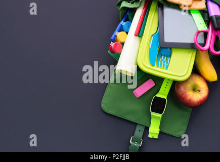 Backpack with school supplies on black background. Top view Flat lay Stock Photo