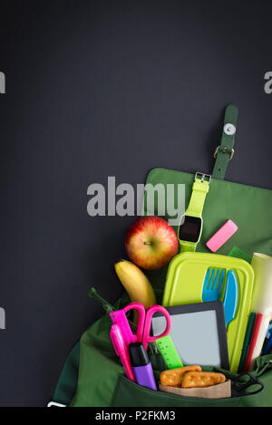Backpack with school supplies on black background. Top view Flat lay Stock Photo