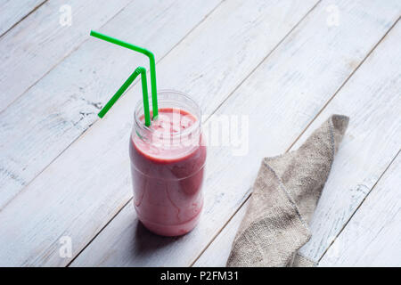 Glass of detox pink strawberry and banana smoothie on white wooden background with copy space. Stock Photo