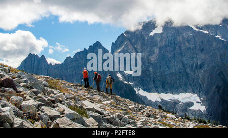 Ben Stilin (left), Melanie Stam (center) and Colin Ayers look out toward Johannesburg Mountain after traversing a talus field in North Cascades National Park, Washington, Sept. 10, 2016. After encountering an exhausted 77-year-old Norman Petty on a hike with his wife Barbara, photographer Capt. Nick Anthony, the pictured climbers and Catherine Mitchell (not pictured) led the couple visiting from Dunwoody, Georgia, to safety by transporting Norman Petty more than three miles using an impromptu support system. Anthony, from Norman, Oklahoma, is a U.S. Marine Corps recruiting management officer b Stock Photo