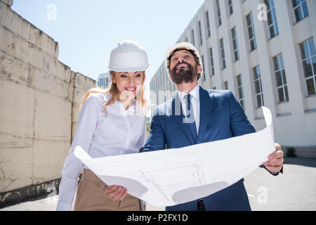 Two smiling architects holding blueprint and working together Stock Photo