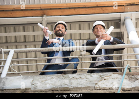 smiling contractors in suits looking at camera on construction site Stock Photo
