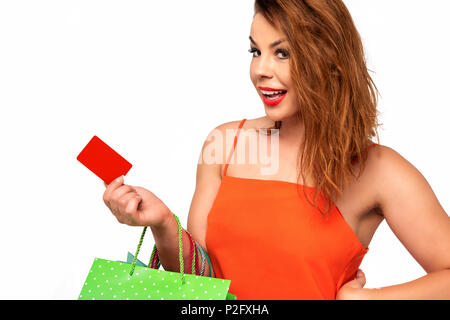 Beautiful woman in an orange dress holds a blank gift card in her hand and enjoys the shopping Stock Photo