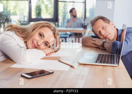 Middle aged business people smiling and lying on wooden table Stock Photo