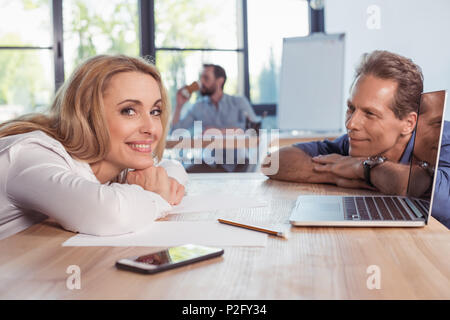 Middle aged business people smiling and lying on wooden table Stock Photo