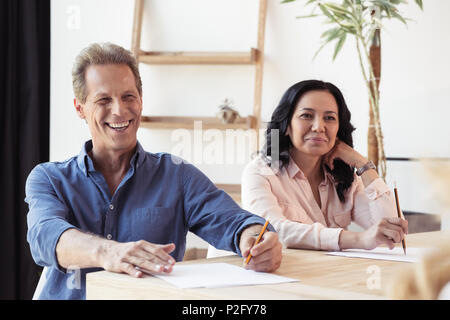 smiling middle aged colleagues making notes at business meeting in office Stock Photo