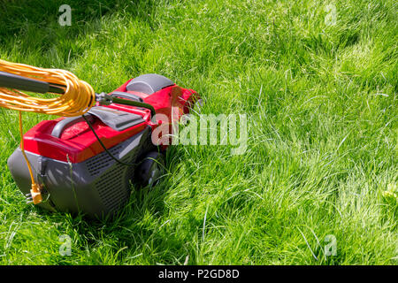 A lawnmower on a lawn of long grass in need of cutting Stock Photo