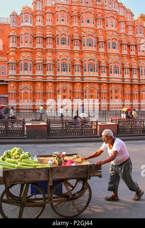 Local man pushing cart in front of Hawa Mahal in Jaipur, Rajasthan, India. It was designed by Lal Chand Ustad in the form of the crown of Krishna, the Stock Photo