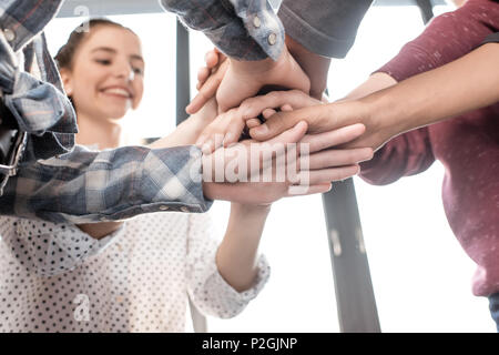 Close-up partial view of teenagers stacking hands together indoors, teenagers having fun concept Stock Photo