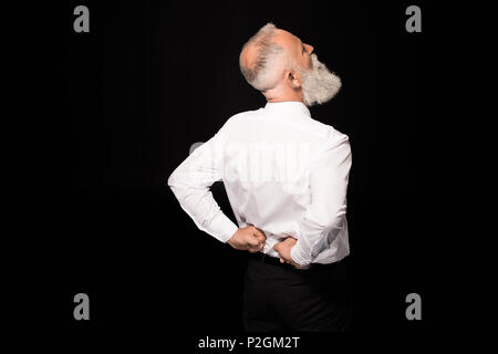Rear view shot of  man in a suit rubbing his lower back Stock Photo
