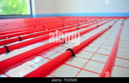 Water underfloor heating pipes on the silver reflective foil in house construction. Stock Photo