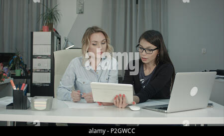 Two female professionals using digital tablet while working at the desk Stock Photo