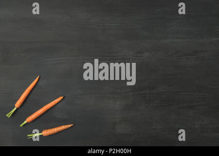 top view of arranged ripe carrots on dark surface Stock Photo