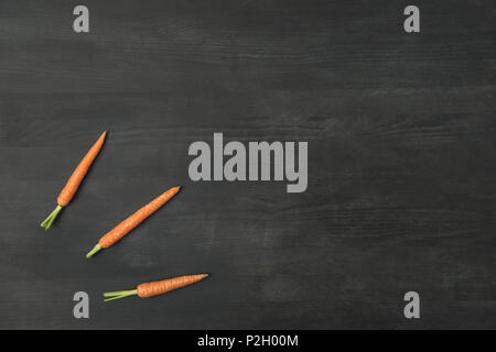 top view of arranged ripe carrots on dark surface Stock Photo
