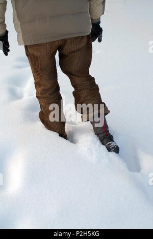 Man wearing winter clothes walking in deep snow, vertical cropped shot Stock Photo