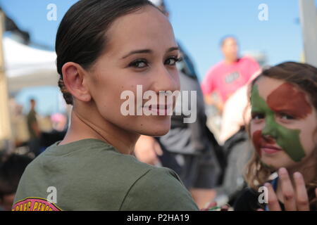 U.S. Marine Lance Cpl. Cameo Prusheik with Marine Air Support Squadron 6, 4th Marine Air Wing, applies camouflage paint on the faces of patrons attending the 2016 Marine Corps Air Station Miramar Air Show at MCAS Miramar, Calif., Sept. 24, 2016. The Air Show marks 100 years of Marine Corps Reserves by showcasing prowess of the armed forces and their appreciation of the civilian community’s support for the troops. (U.S. Marine Corps photo by Pfc. Nadia J. Stark/Not Released) Stock Photo