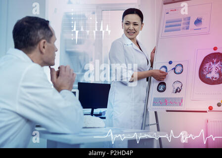 Attentive doctor looking at the scheme while his colleague talking about brains Stock Photo