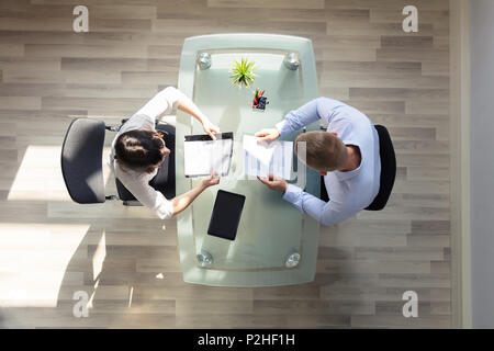 Elevated View Of Two Businesspeople Holding Resume Over Desk In Office Stock Photo