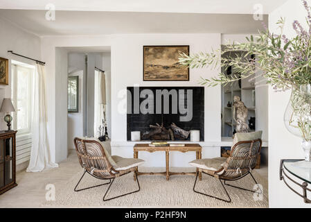 Pair of vintage wooden armchairs in front of fireplace in 18th century Luberon home. Stock Photo
