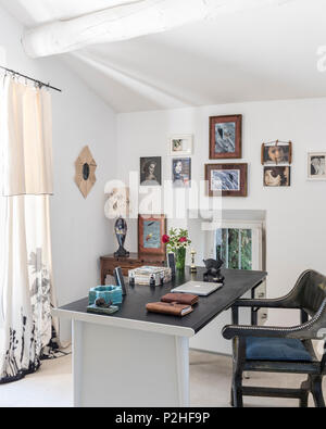 Framed portraits with desk and chair in 18th century Luberon home. Stock Photo