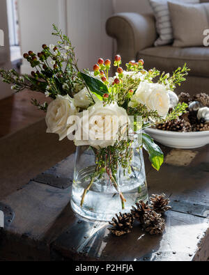 Detail of vase of roses on old trunk with decorative pine cones Stock Photo