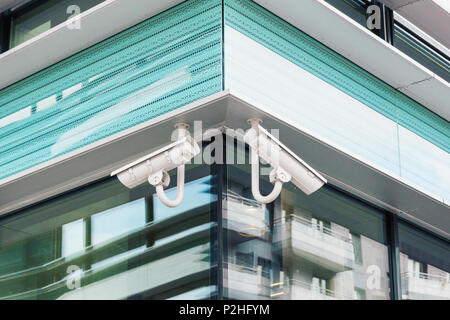 Two modern cctv security cameras on modern steel and glass building facade Stock Photo