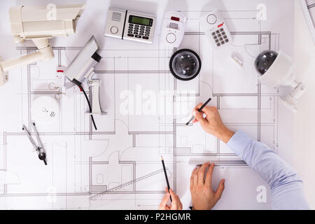 Various Security Equipments In Front Of Two Architects Planning Project On Blueprint Stock Photo