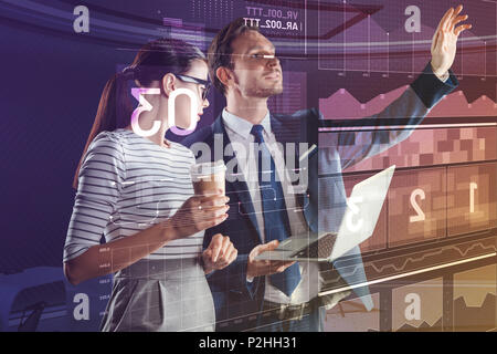 Young man holding a laptop while his colleague drinking coffee Stock Photo