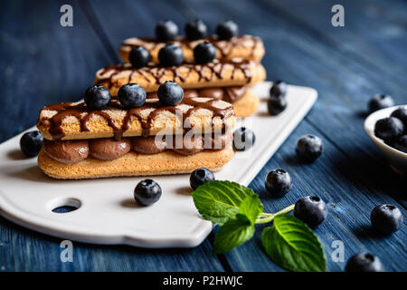 Ladyfingers filled with cocoa mascarpone cream, topped with chocolate and blueberry Stock Photo