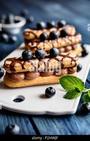 Ladyfingers filled with cocoa mascarpone cream, topped with chocolate and blueberry Stock Photo