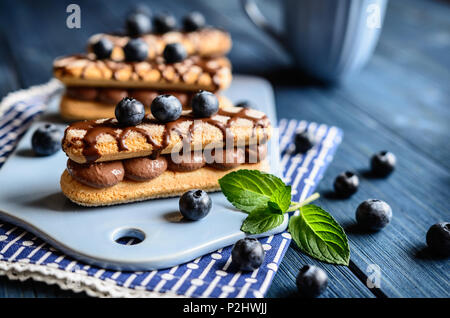 Ladyfingers filled with cocoa mascarpone cream, topped with chocolate and blueberry Stock Photo