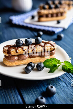 Ladyfingers filled with cocoa mascarpone cream, topped with chocolate and blueberry Stock Photo