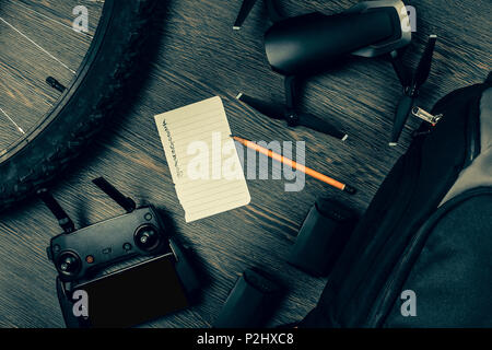 drone and its accessories on a wooden background near a bicycle sheet of paper to write a plan of air filming, toned image Stock Photo