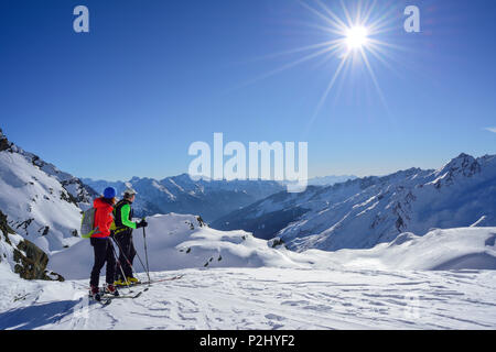 Two persons back-country skiing looking towards Zillertal Alps and Stubai Alps, Schneespitze, valley of Pflersch, Stubai Alps, S Stock Photo
