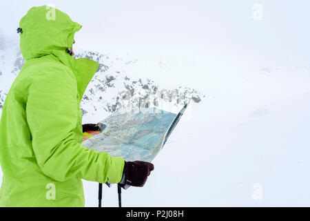 Woman back-country skiing studying map during bad weather, Serriera di Pignal, Valle Stura, Cottian Alps, Piedmont, Italy Stock Photo