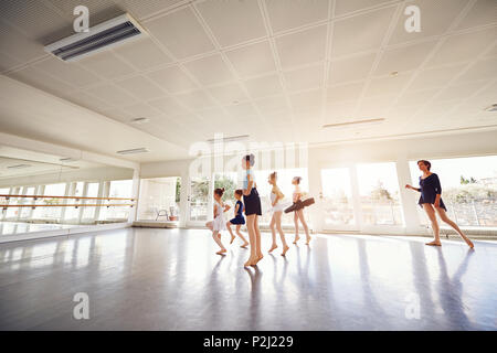 Young elegant small girls dancing ballet while teacher watching in class. Stock Photo