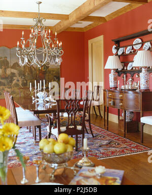 Ornate metal chandelier above table in red country dining room Stock Photo