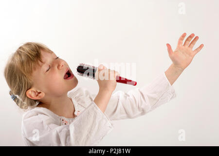 Hairbrush diva or divas. Young girl singing into her hairbrush Stock Photo