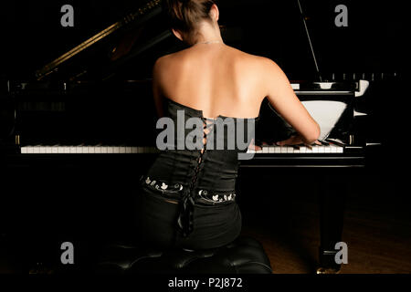 young woman playing the piano back view. Stock Photo