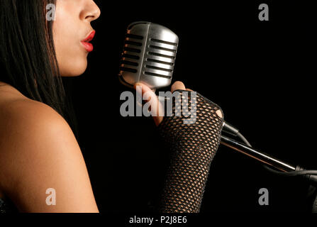 young woman singing into a mic Stock Photo
