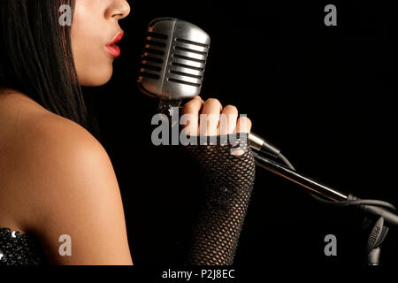 young woman singing into a mic Stock Photo
