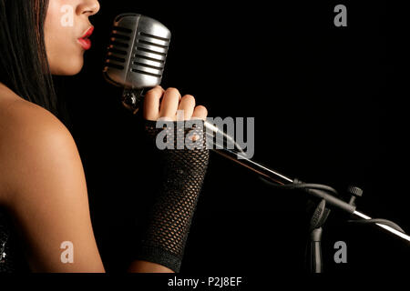 young woman singing into a mic Stock Photo