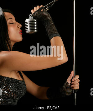 young woman singing into a mic Stock Photo