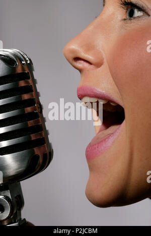young woman singing into a mic Stock Photo